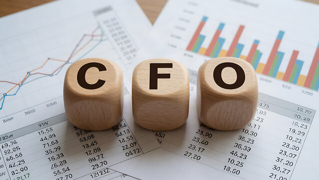 CFO wooden letter blocks resting on financial charts and spreadsheets
