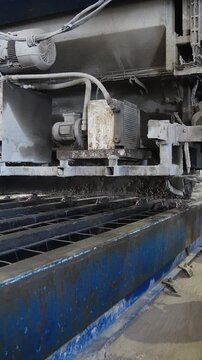 Concrete casting machine moving along long steel molds at a concrete plant