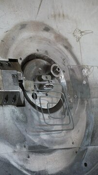 Rebar bending machine forming a steel wire spiral behind a safety guard at a factory