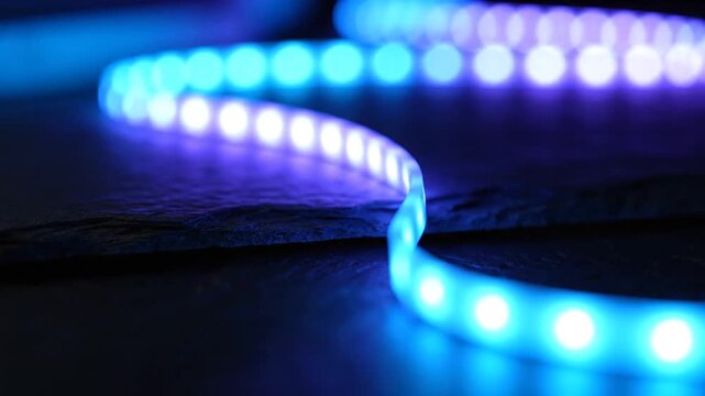 Vibrant blue led light strip glowing dynamically on dark textured surface