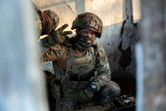 Soldier operates a drone control console. Military personnel is carrying out a combat mission at a position in an abandoned house.