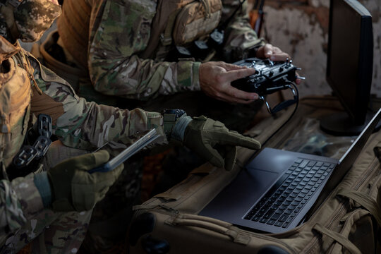 Soldiers operate a drone control console. Military personnel are carrying out a combat mission at a position in an abandoned house.