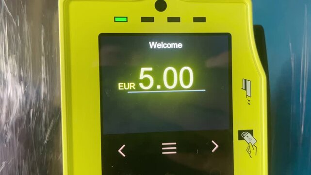 A bright yellow credit card reader with a welcoming message creates a userfriendly experience, displaying a balance of 5.00 for easy payments