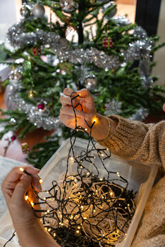 Hands untangling christmas fairy lights for holiday decoration
