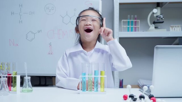 Asian girl student scientist having a bright idea pointing finger while conducting chemistry experiment with test tubes in school laboratory for stem education and academic research discovery