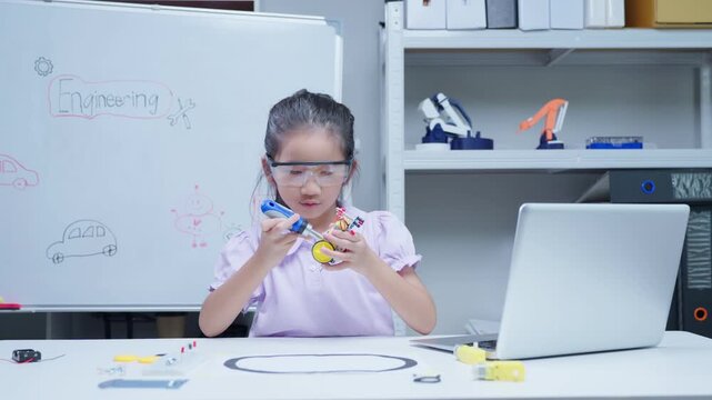 Young female student assembling robotic car kit in engineering science laboratory