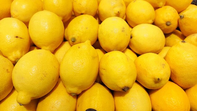 A full-frame overhead view showing a large pile of fresh yellow lemons, filling the entire frame with striking fruit textures.