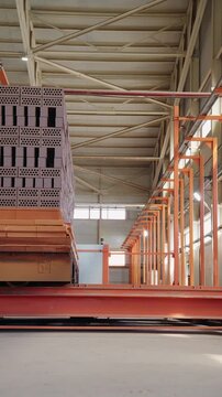 Kiln car loaded with clay bricks moving through a brick factory hall