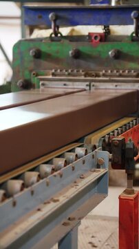 Extruded clay column moving out of a brick extruder onto a roller conveyor