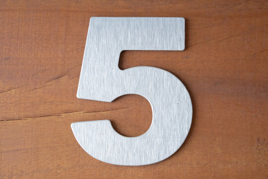 Horizontal wide-angle view of a brushed stainless steel digit five affixed to a rustic timber surface