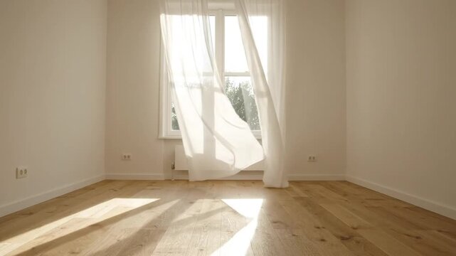 White sheer curtains blowing in the wind inside an empty room with wooden floor