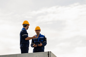 Fototapeta premium Engineer industrial worker in safety helmet discussing construction plan on concrete structure under cloudy sky