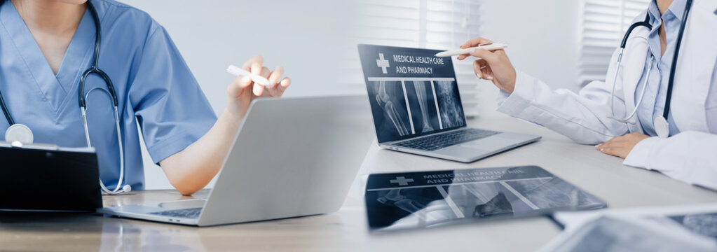 A professional doctor examining a patient's X-ray scan on a laptop computer in a modern hospital or clinic room..