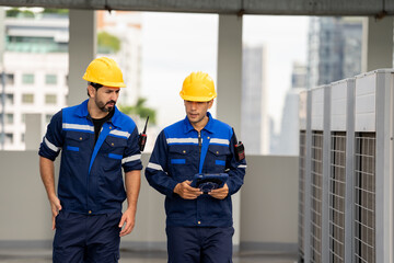 Obraz premium Industrial engineer engineer worker man technician construction maintenance machinery rooftop uniform helmet industrial engineer inspecting rooftop machinery with tablet while colleague walks