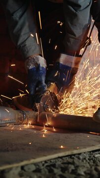 Angle grinder cutting a steel pipe with a shower of sparks at a construction site