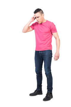 Full body of shocked young male with dark hair in casual outfit touching forehead and looking down