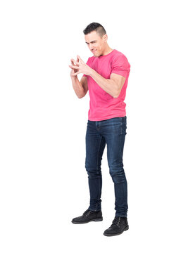 Full length of cunning young man with dark hair in t shirt and jeans connecting fingers and looking at camera