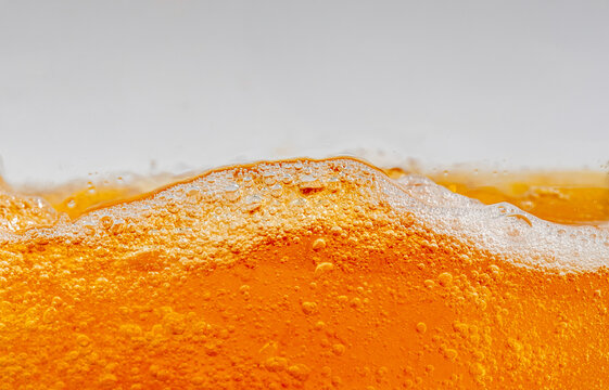 Close up of golden beer splashing with bubbles and foam in a glass, creating dynamic liquid movement. Refreshing alcoholic drink background for commercial beverage advertising and design