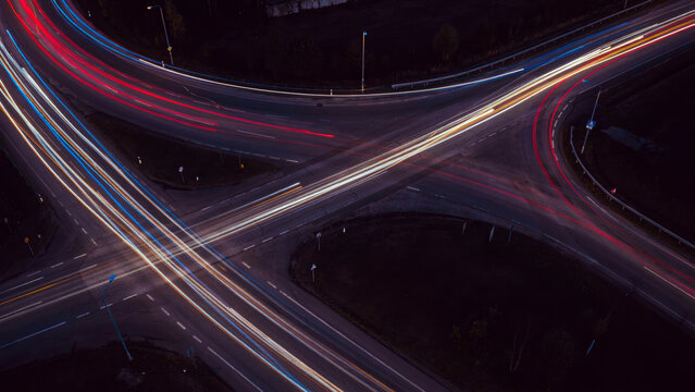 Abstract long exposure photograph showcasing vibrant red and blue light trails converging on a dark asphalt surface