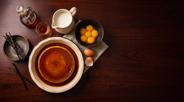 Overhead flat lay of Mexican vanilla beans and caramel flan on mahogany table