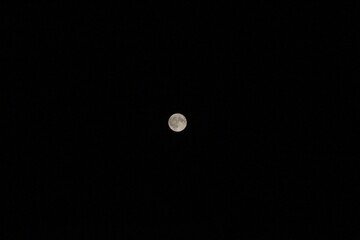 A bright full moon isolated against a deep black night sky. © Inna Trokhymets 