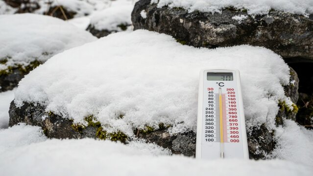 A digital thermometer measuring sub-zero temperatures outdoors in deep winter snow. Perfect for weather forecasting and climate change conceptual designs.