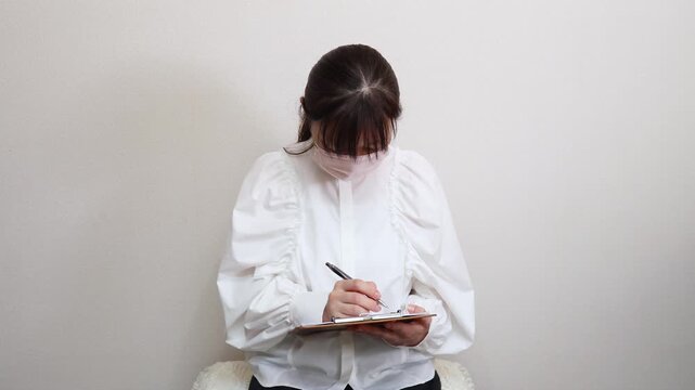 マスクをした女性　問診票に記入する様子