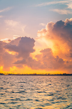 Dramatic sunset glowing golden fiery clouds vivid sky calm tropical sea ocean horizon evening summer paradise vertical. Peaceful summer sunset scene nature. Atmospheric romantic coastal wellness relax
