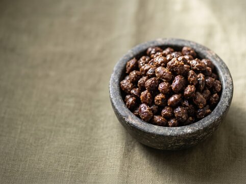 Bowl of roasted chickpeas sitting on textured fabric surface