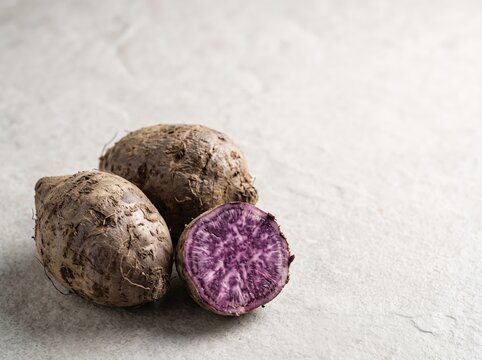 Purple yam tubers sliced to reveal vibrant interior on surface