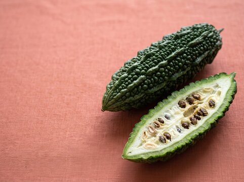 Bitter melon halved with seeds on textured cloth surface