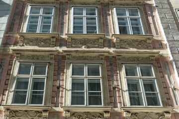 Ornate historic building facade with symmetrical windows and sunlit stonework © Anelo