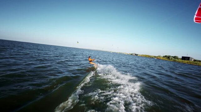 Woman kiteboarding on water with wake spray