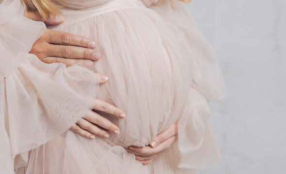 pregnant woman in an elegant fitted dress gently cradling her belly, pregnancy motherhood maternity portrait