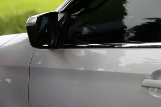 Side view mirror of a white modern car with raindrops