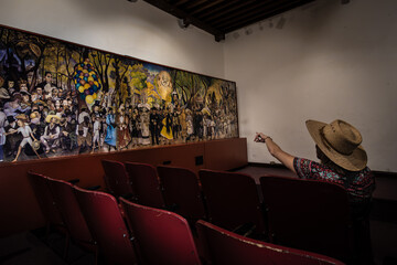 Woman pointing at mural in old theater in Mexico © Steve's Photos