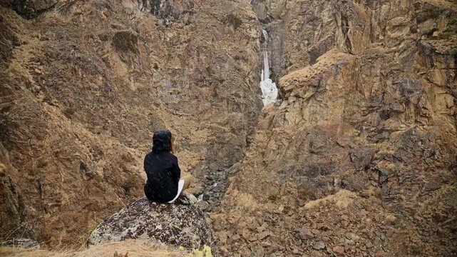 Person sitting on boulder in rocky ravine