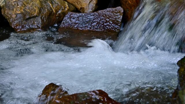 Water cascade flowing rapidly over wet rocks