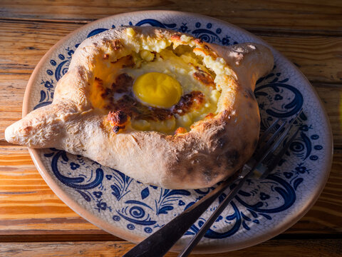 Adjarian Khachapuri (Adjaruli Khachapuri) famous Georgian boat shaped cheese bread topped with a raw egg yolk and butter from the coastal Adjara region on the Black Sea