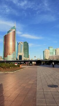 Viewing Transport Tower on Nurzhol Boulevard in Astana, with copper facade, modern skyscrapers, pedestrian plaza and clear blue sky, Kazakhstan, shot handheld, vertical video, 4k footage