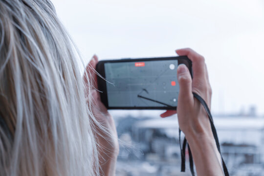Person photographing ship masts on smartphone screen Person holding modern smartphone and taking picture of historic ship masts and harbor structures on camera screen