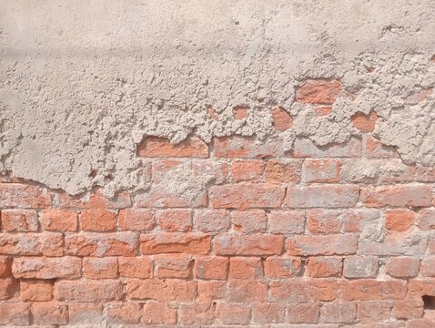 Old brick wall photo background. Weathered red clay bricks with crumbling grey plaster texture. Rough damaged masonry surface for industrial design and grunge architecture.