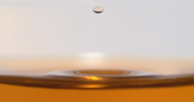 Black tea droplet falling into tea creating splash in super slow motion