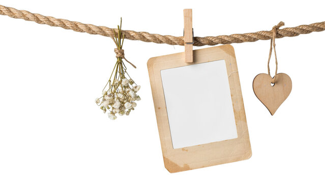 Vintage polaroid paper photo frame hanging on rustic twine rope with wooden clothespin isolated white.