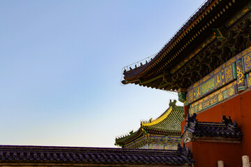 Detailed view of traditional Chinese imperial palace architecture featuring ornate colorful eaves and glazed tiled roofs under a clear sky. © Pei Yan
