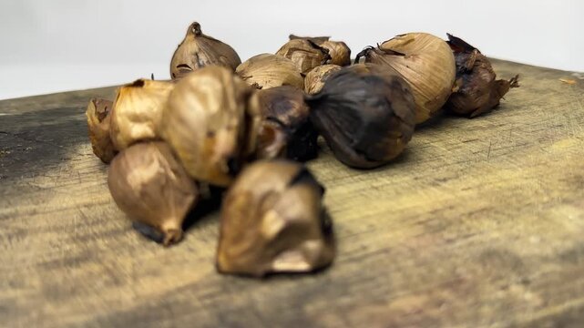 Single clove black garlic for herbal use on a wooden board