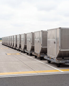 Row of aluminium air cargo containers on dollies at an airport apron