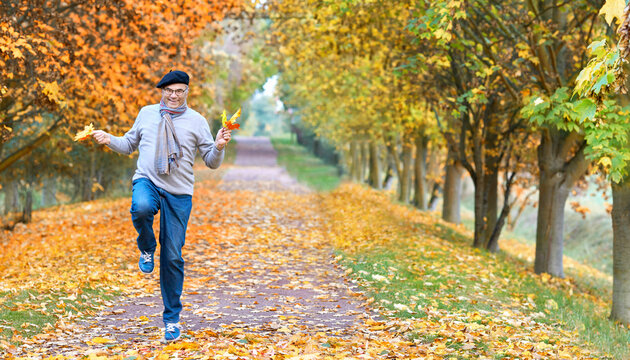 happy smiling senior is jumping through the autumn park