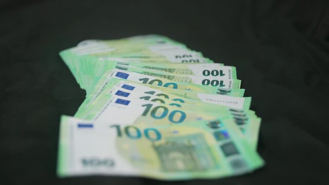 Extreme macro shot of 100 Euro banknotes falling on a black background
