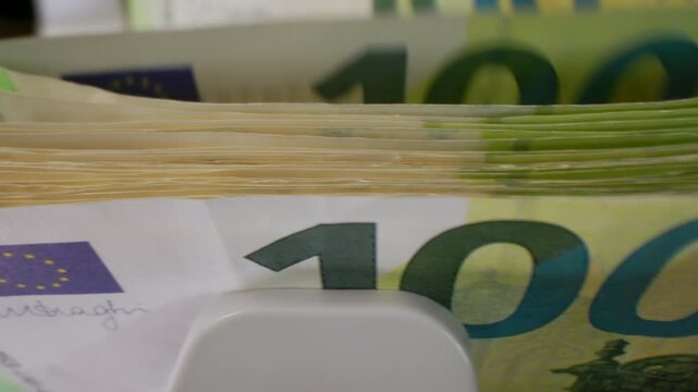 Extreme macro shot of 100 Euro banknotes in a rapid cash counting machine